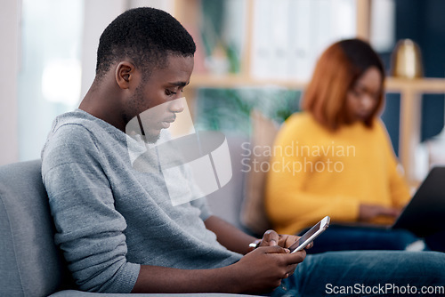 Image of Relax, phone or technology addiction and a black man on the living room sofa of his home with his girlfriend on a blurred background. Mobile, contact and social media with a male person in a house