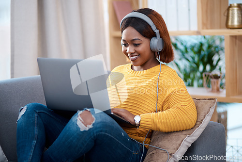 Image of Black woman with laptop, headphones and relax on sofa, search online for movie and streaming subscription at home. Happy African female person in apartment, connectivity and watching on pc with web