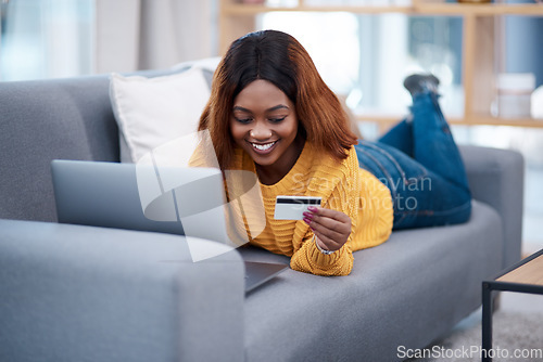 Image of Black woman, laptop and credit card with online shopping, e commerce with payment on store website and relax on sofa. Happy African female customer, bank app and finance with internet banking at home