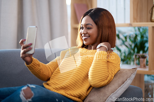 Image of Black woman in her home, selfie and relax on couch in living room, lifestyle influencer and social media post. African female content creator in apartment, smile in picture and communication with app