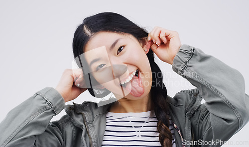 Image of Portrait, funny face and ears with an asian woman in studio on a gray background looking silly or goofy. Comedy, comic and crazy with a playful young female person joking indoor for fun or humor