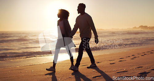 Image of Couple holding hands, walking on beach at sunset and ocean with silhouette, vacation and travel with mockup space. Love, romance and trust with people in commitment, tropical holiday and sea view