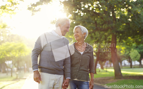 Image of Senior couple, walking and holding hands outdoor at a park with love, care and support. A elderly man and woman in nature for a walk, quality time and communication for healthy marriage or retirement