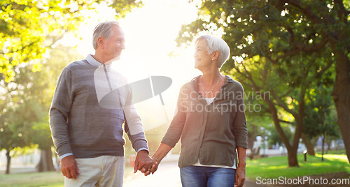 Image of Happy, walking and a senior couple outdoor at a park with love, care and support. A elderly man and woman holding hands in nature for commitment, quality time and healthy marriage or retirement