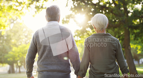 Image of Senior couple, walking and outdoor at a park with a love, care and support from back. A elderly man and woman holding hands in nature for a walk, quality time and healthy marriage or retirement