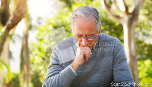 Image of Depression, park and senior man crying while sitting on a bench thinking on mental health problem. Nature, outdoor and sad elderly male person in retirement with grief stress after loss in a garden.