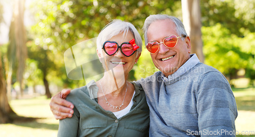Image of Senior couple, funny glasses and portrait outdoor at a park with love, care and heart shape. A elderly man and woman with comic sunglasses in nature for happiness, healthy marriage and retirement