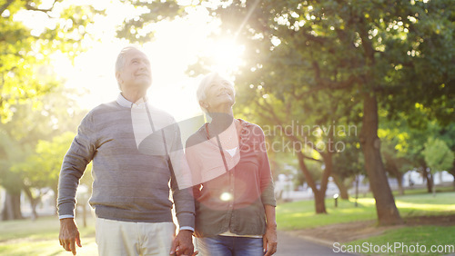 Image of Senior couple, holding hands and walking outdoor at a park with love, care and support. A elderly man and woman in nature for a walk, quality time and hope for a healthy marriage or retirement