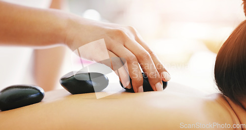 Image of Woman, hands and rock massage at spa in relax for zen, physical therapy or treatment at resort. Hand of masseuse and female person with hot stone back for muscle relief, peace or wellness at a salon