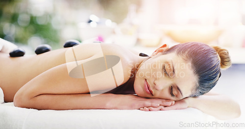 Image of Woman, relax and rock massage at spa sleeping for healthy wellness, skincare or stress relief at the resort. Calm female person relaxing in peaceful zen, hot stone back or body treatment at the salon