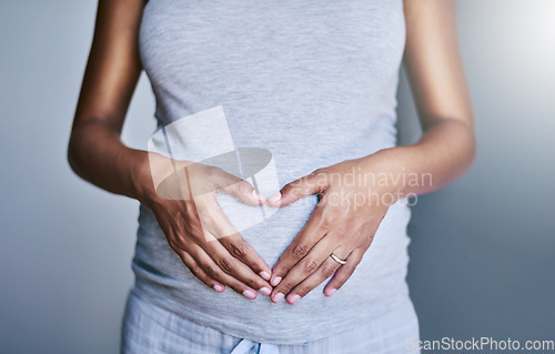 Image of Pregnancy, woman and heart hands on her stomach for love, care and maternity in her house. Bonding, maternal and closeup of a pregnant female person holding her belly for motherhood at her home.