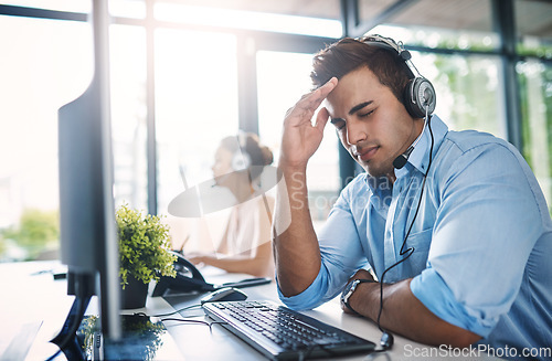 Image of Businessman, call center and headache in burnout, stress or overworked strain at the office. Tired or stressed man person, consultant or agent with bad head pain, migraine or anxiety in contact us