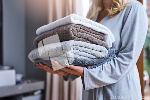 Image of Laundry, cleaning and a woman with a stack of towels in her home for hygiene or a spring clean day. Housework, housewife and a female person carrying a pile of fresh or soft fabric in a living room