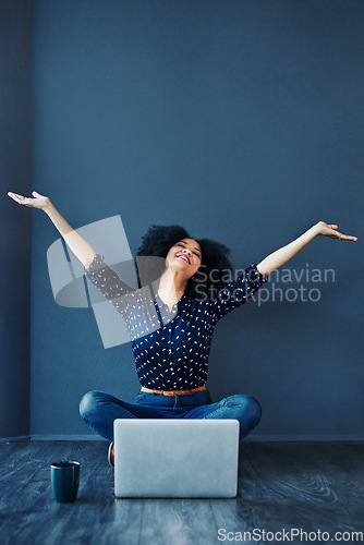 Image of Laptop, success and businesswoman in celebration on the floor by a blue wall with a mug. Happy, smile and excited professional female employee with an achievement or goals to celebrate with computer.