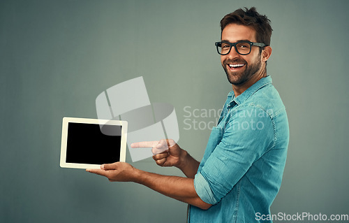 Image of Happy man, tablet and pointing to mockup screen for advertising against a grey studio background. Portrait of male person smiling showing technology display, chromakey or copy space for advertisement