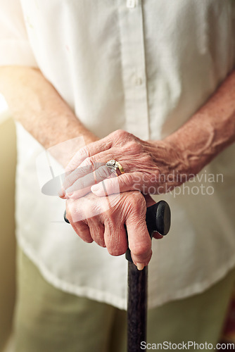 Image of Hands, cane and closeup of senior woman with disabled injury with balance in retirement in house. Walking stick, elderly lady and person with disability, support or recovery in home with lens flare