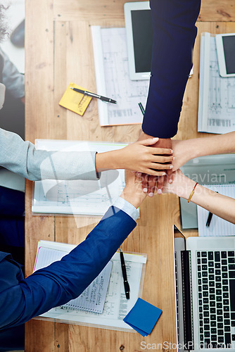 Image of Top view, business people and stack hands at table in support of goals, synergy and target of success, agreement and trust. Closeup, integration and collaboration of teamwork in a winning circle