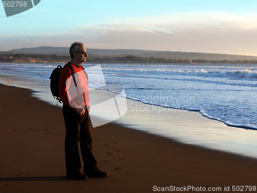 Image of Man enjoying sunset by the ocean