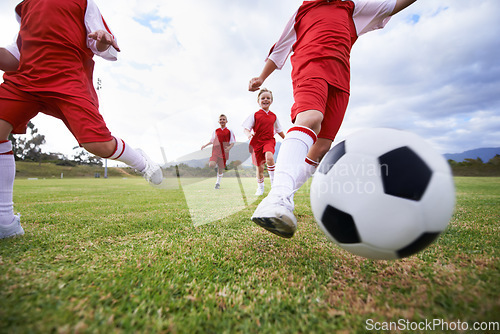 Image of Running, teamwork and closeup with children and soccer ball on field for training, competition and fitness. Game, summer and action with football player and kick on pitch for goals, energy or athlete