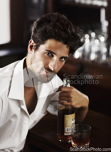 Image of Man, pub counter and portrait with drink at happy hour with alcohol and whiskey after work. Bottle, male person and face of a handsome guy with a glass and style and confidence in a luxury bar