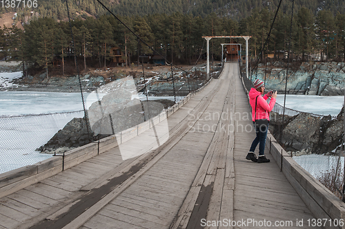 Image of Happy woman taking photos on the bridge