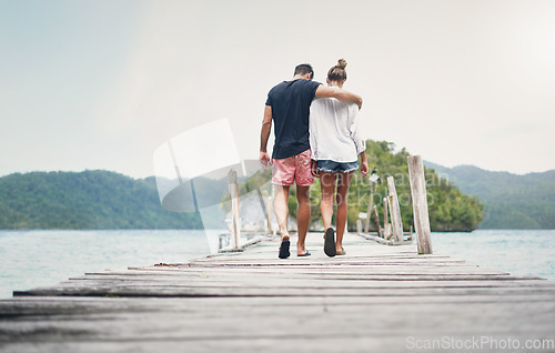 Image of Couple, vacation and walking on ocean boardwalk for travel, freedom and peace. Back of a man and woman hug and walk to relax on Indonesia holiday, tropical adventure or nature date at sea on a deck