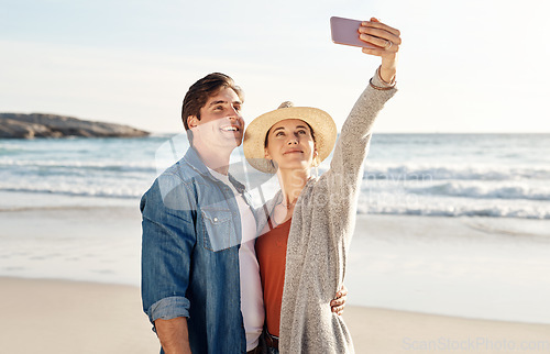 Image of Young couple, beach selfie and happy in summer sunshine for love, romance or smile for social media post. Man, woman and profile picture for blog, app or internet by ocean, waves or sea for holiday