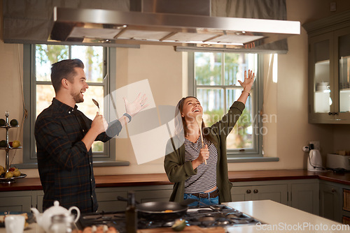 Image of Food, sing and a funny couple in the kitchen of their home, having fun together while cooking. Karaoke, silly or comic with a man and woman laughing while singing over breakfast in their house