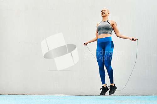 Image of Jump, rope and woman skipping against space in stadium for sports, workout practice and cardio. Performance, health and body with female athlete training on track for strong, mockup and exercise