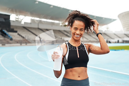 Image of Fitness, running and portrait of happy woman with water at stadium, relax at marathon training or exercise. Workout, health and body, female sports runner at arena track with smile and bottle.