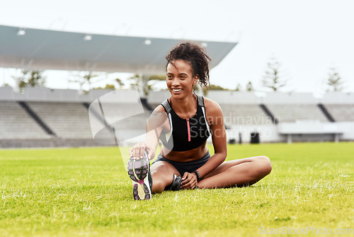 Image of Happy woman, athlete and stretching legs on grass at stadium getting ready for running, workout or exercise. Active female person or runner in warm up leg stretch, athletic fitness or sports on field