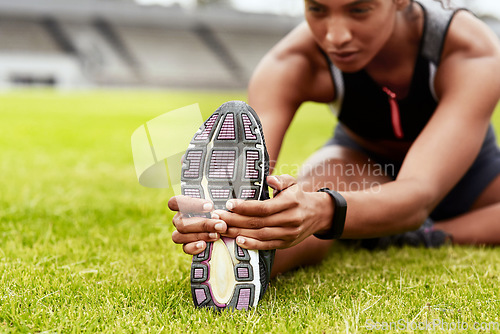 Image of Woman, hands and stretching legs on grass at stadium in preparation for running, exercise or workout. Hand of active female person in warm up leg stretch, fitness or sports motivation on the field