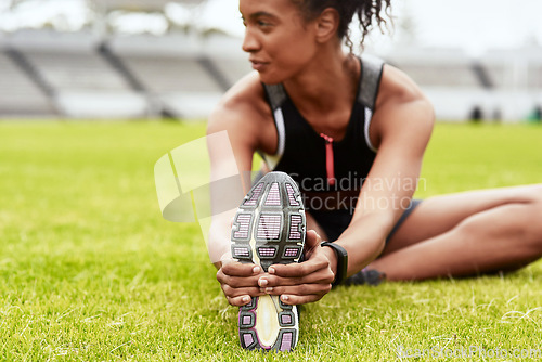 Image of Woman, hands and athlete stretching legs on grass at stadium in preparation for running, exercise or workout. Active or fit female person in warm up leg stretch for fitness, sports or run on field