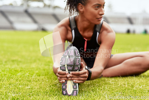 Image of Woman, athlete and stretching legs on grass at stadium in preparation for running, exercise or workout. Active or fit female person in warm up leg stretch for fitness, sports or run on the field