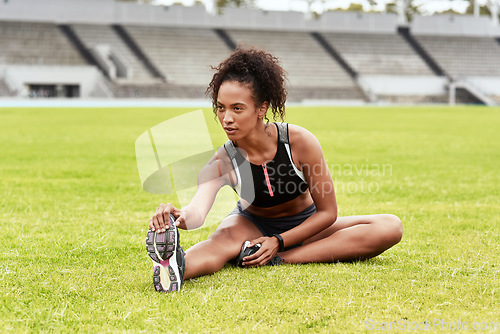 Image of Woman, athlete and stretching legs on grass at stadium getting ready for running, workout or exercise. Active and sporty female person or runner in warm up leg stretch, athletics or fitness on field