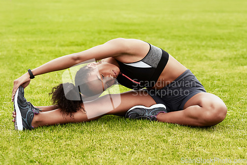 Image of Woman, athlete and stretching body on grass in preparation for running, exercise or workout. Active or fit female person in warm up leg stretch for fitness, sports training or cardio run on the field