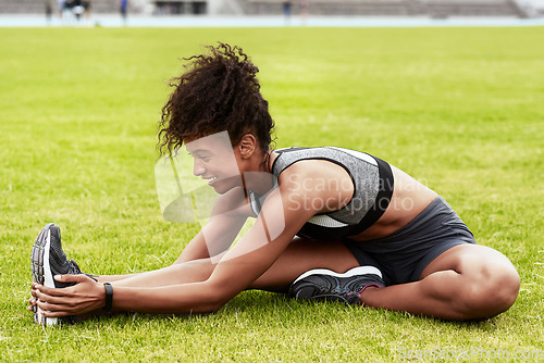 Image of Happy woman, athlete and stretching body on grass for running, exercise or workout at the stadium. Active female person in warm up leg stretch for fitness, sports training or cardio run on the field