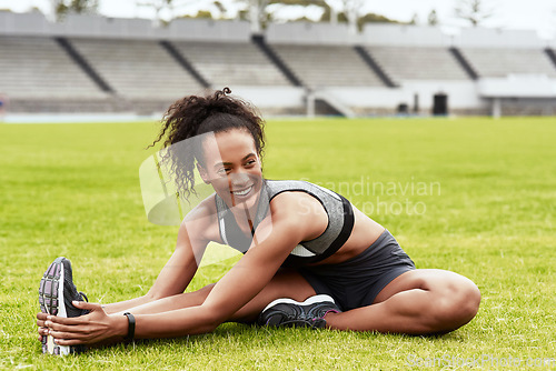 Image of Happy woman, fitness and stretching body on grass for running, exercise or workout at the stadium. Active female person or athlete in warm up leg stretch for sports training or cardio run on a field