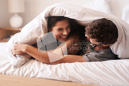 Image of Blanket, smile and couple with love, home and peace with happiness, romance and loving together. Partners, man and woman in the bedroom, peace and romantic with peace, laughing and bonding at home
