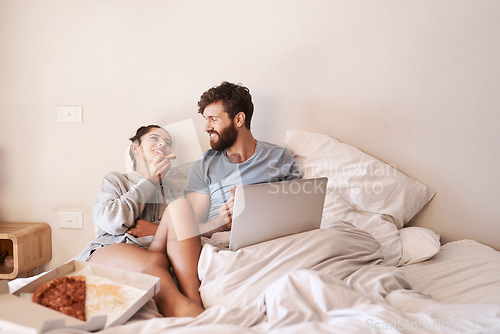 Image of Couple laugh, pizza and movie on laptop in bed with junk food and streaming series. Eating, computer video and meal in a bedroom at home with man and woman together with bonding and online watching