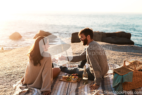 Image of Picnic, beach and couple with champagne happy for relax, bonding and quality time on romantic date. Nature, dating and man and woman toast for anniversary, honeymoon and love on holiday or vacation