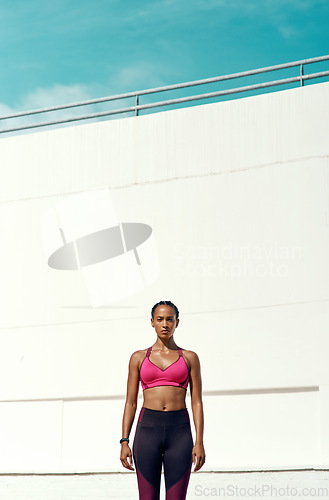 Image of Sports, workout and portrait of serious woman with mockup, blue sky and vertical wall background at outdoor gym. Fitness, exercise and athlete with focus, sweat and healthy mindset for summer goals.