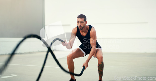 Image of Man, fitness and battle rope exercise for physical training, workout or wellness in the outdoors. Fit, active and serious male person exercising with ropes for intense endurance, stamina or cardio