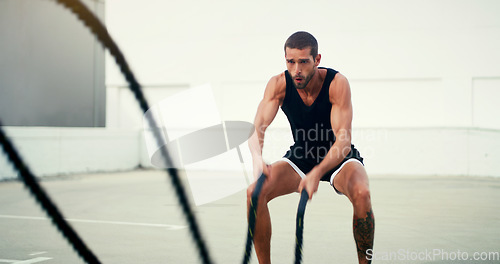 Image of Man, fitness and battle rope workout for physical training, exercise or wellness in the outdoors. Fit, active and serious male person exercising with ropes for intense endurance, stamina or cardio