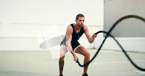 Image of Man, fitness and battle rope training for physical exercise, workout or wellness in the outdoors. Fit, active and serious male person exercising with ropes for intense endurance, stamina or cardio