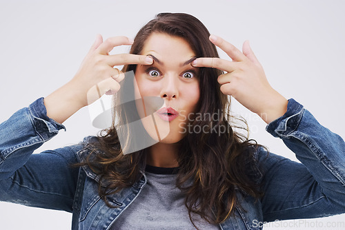 Image of Portrait, funny face and eyes with a woman in studio on a gray background looking silly or goofy. Comedy, comic and crazy with a playful young female person joking indoor for fun or carefree humor