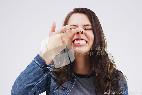 Image of Smile, funny face and nose with a crazy woman in studio on a white background for carefree humor. Comic, comedy and showing nostrils with a weird young female person feeling playful while joking