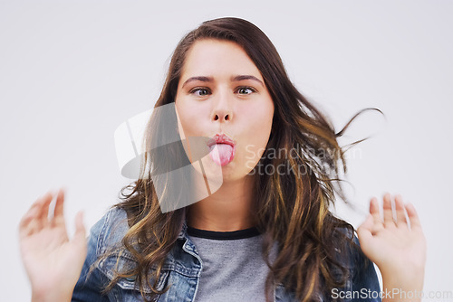 Image of Portrait, funny face and tongue with a woman in studio on a white background looking silly or goofy. Comedy, comic or crazy and a playful young female person joking indoor for humor with an emoji