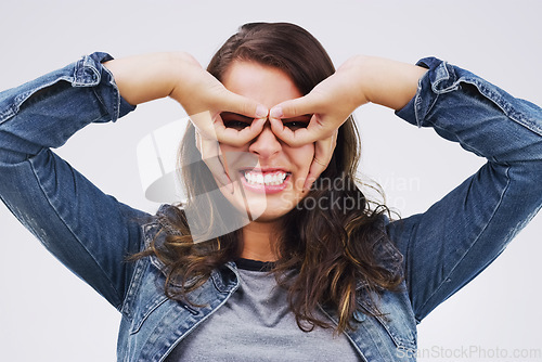 Image of Portrait, funny face and finger glasses with a woman in studio on a white background looking silly or goofy. Comedy, comic and smile with a crazy young female person joking indoor for fun or humor