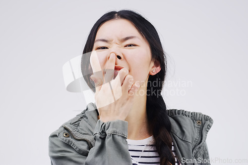 Image of Portrait, funny face and nose with an asian woman in studio on gray background looking silly or goofy. Comedy, comic and crazy with a happy young female person joking indoor for playful fun or humor